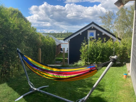 Garten mit Rasen, Terrasse, brasilianischer Hängematte und Weg zum privaten Anlegesteg.